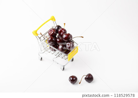 Cherry in a miniature (small) grocery cart for a supermarket. Toy cart with berries on a white background. Close-up, Copy space for text, top view. Cherry in a miniature (small) grocery cart for a supermarket. Toy cart with berries on a white background. Close-up, Copy space for text, top view. 118529578