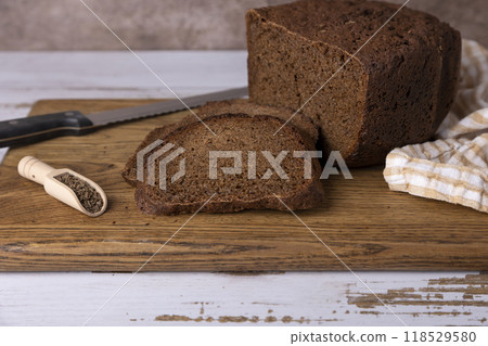 Rye Borodino (Borodinskiy) bread with a crispy crust on a wooden board, cut into slices. Homemade baking in rustic style. Selective focus, close-up. 118529580
