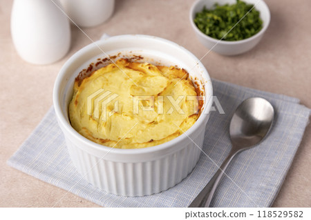 Shepherd's pie in a portioned white baking dish. Homemade traditional casserole (gratin) with minced meat and mashed potatoes. Selective focus, close-up. 118529582