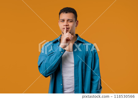 Handsome man with gesture of shh, secret, silence, conspiracy, gossip on yellow Handsome man with gesture of shh, secret, silence, conspiracy, gossip on yellow 118530566