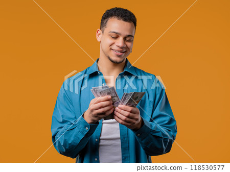 Rich african american man with Usd money on yellow background. Young Guy Or Student counting salary, scholarship payment. Jackpot, win Rich african american man with Usd money on yellow background. Young Guy Or Student counting salary, scholarship payment. Jackpot, win 118530577