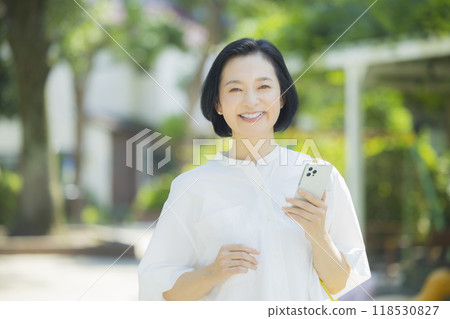 Smiling middle-aged woman holding a smartphone 118530827
