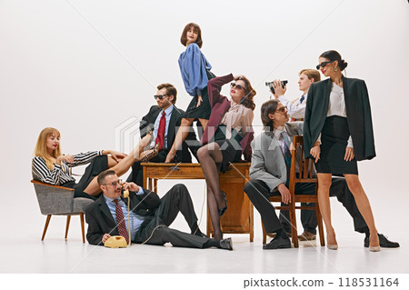 Office moment, where group playfully gathers around desk, showing more laid-back side of business life against white studio background. 118531164