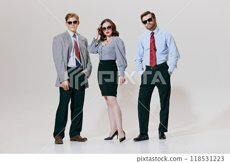 Three stylish professionals strike confident pose in trendy business attire against white studio background. Modern twist to classic corporate fashion. Three stylish professionals strike confident pose in trendy business attire against white studio background. Modern twist to classic corporate fashion. 118531223