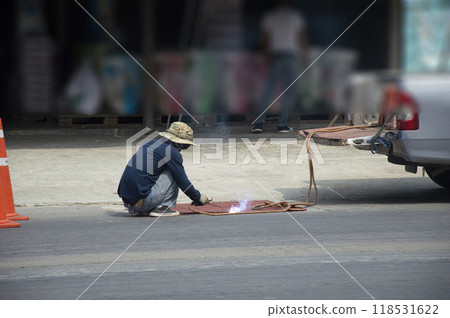 Technicians are repairing and welding a manhole cover on a road. Technicians are repairing and welding a manhole cover on a road. 118531622