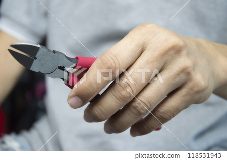 Mechanic holds red handle cutting pliers, mechanic's tools 118531943