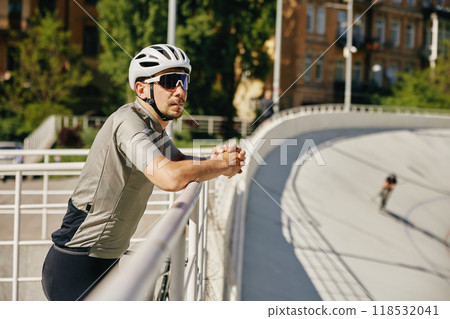 Relaxed bicyclist taking rest watching training at velodrome Relaxed bicyclist taking rest watching training at velodrome 118532041