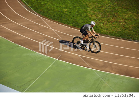 Man bicyclist enjoying training cycling on open velodrome track view from afar Man bicyclist enjoying training cycling on open velodrome track view from afar 118532043