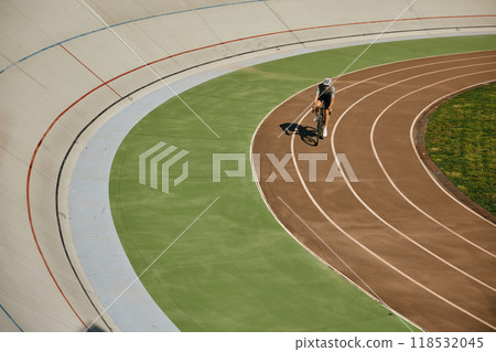 Man bicyclist enjoying training cycling on open velodrome track view from afar Man bicyclist enjoying training cycling on open velodrome track view from afar 118532045