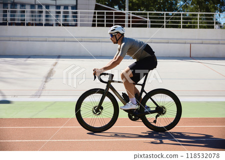 Confident bicyclist wearing sports clothing and protective helmet cycling on track 118532078