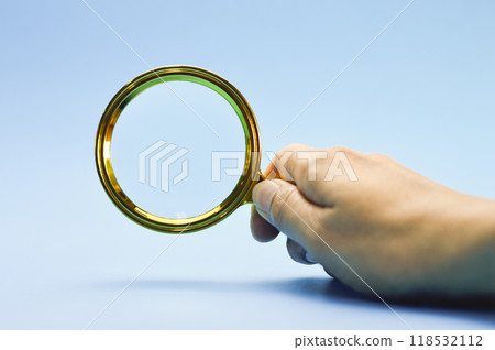 Male hand holding a magnifying glass blue background Male hand holding a magnifying glass blue background 118532112