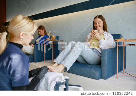 Two happy women clients deinking wine speaking at pedicure procedure 118532242
