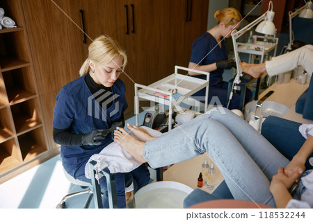 Pedicure specialist filing down toe nail plate with polishing brush 118532244