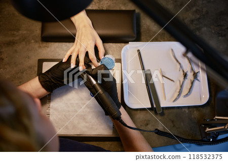 Top view on manicurist using multifunctional device for manicure 118532375