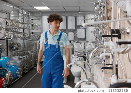 Male plumber selecting stainless steel washbasin water tap at store Male plumber selecting stainless steel washbasin water tap at store 118532386