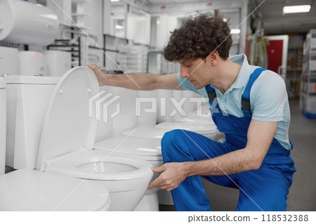 Plumber choosing toilet bowl on retail display at plumbing shop 118532388