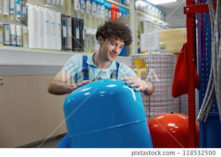 Portrait of plumber carrying hydraulic tank bought at plumbing shop 118532500