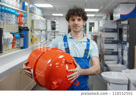 Portrait of plumber carrying hydraulic tank bought at plumbing shop Portrait of plumber carrying hydraulic tank bought at plumbing shop 118532501