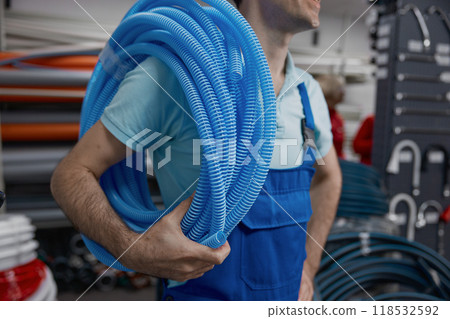 Plumber holding roll of corrugated plastic water pipe 118532592