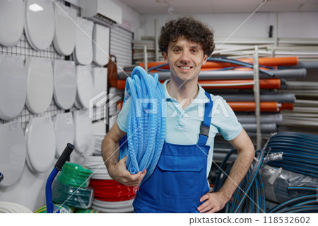 Portrait of happy smiling plumber holding roll of corrugated plastic water pipe 118532602