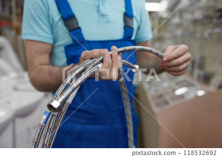 Cropped shot of man plumber holding plumbing hoses at shopping mall Cropped shot of man plumber holding plumbing hoses at shopping mall 118532692