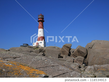 Red and white cast iron Eigeroy Lighthouse and anorthosite rock formations, Norway. Red and white cast iron Eigeroy Lighthouse and anorthosite rock formations, Norway. 118534913