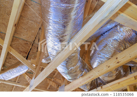 Installation of silver insulation ventilation HVAC pipes from ceiling to roof during construction Installation of silver insulation ventilation HVAC pipes from ceiling to roof during construction 118535066