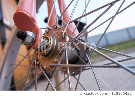 Close-up view of a bicycle wheel hub and spokes at sunset outdoors Close-up view of a bicycle wheel hub and spokes at sunset outdoors 118535422