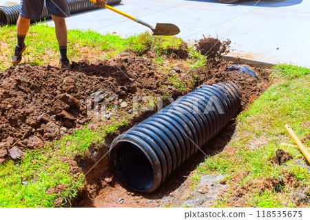 Installation of drainage black pipe in trench during construction Installation of drainage black pipe in trench during construction 118535675