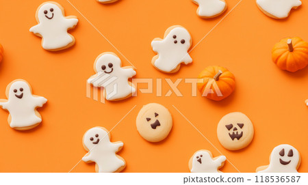A pattern of cookies in the shape of smiling ghosts and pumpkins on an orange background. Halloween pattern 118536587