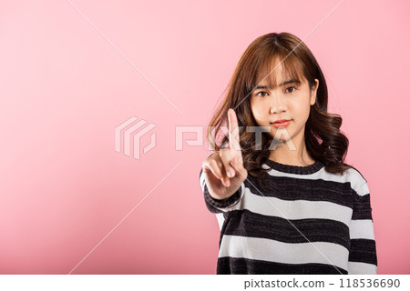 Portrait Asian confident young woman showing one finger for stop gesture studio short isolated on pink background, female telling to stop in disapproval prohibit something 118536690