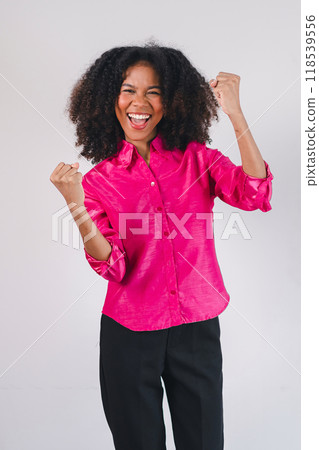 Joyful African American woman celebrating success with raised fists, expressing excitement and happiness. 118539556