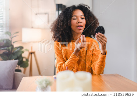 Pretty woman with curly hair putting on makeup at home. Pretty woman with curly hair putting on makeup at home. 118539629
