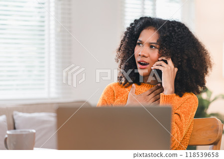 African American woman having phone conversation while working at desk with laptop. African American woman having phone conversation while working at desk with laptop. 118539658