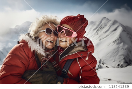 Couple of elderly women clad in ski gear share a heartwarming embrace at the snowy summit of a mountain 118541289