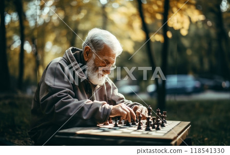 An elderly man engages in a game of chess, contemplating each move thoughtfully, surrounded by the tranquility of the outdoors, blending intellectual pursuit with the beauty of nature 118541330