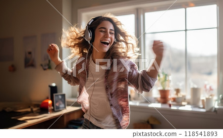 In the comfort of her modern home, a stylish woman immerses herself in the joy of music, donning headphones as she gracefully dances, creating a dynamic and expressive atmosphere within her domestic 118541893