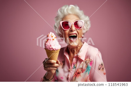 An elegant older woman, adorned with stylish sunglasses, enjoys a moment of indulgence as she savors ice cream, creating a vibrant and modern image against an isolated pink background 118541963