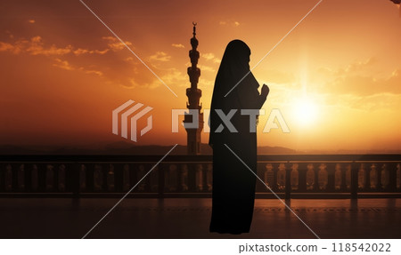 Silhouettes of a Muslim man and woman praying at a sacred site, bathed in the golden light of sunrise and sunset.Generated image 118542022