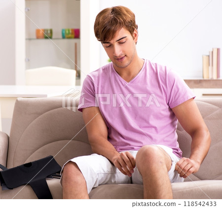 Injured man recovering at home from sports injury 118542433