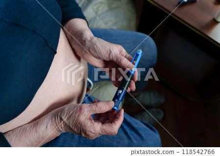 wrinkled fingers of an elderly person delicately hold an injection device, routine of insulin administration to control a chronic health condition wrinkled fingers of an elderly person delicately hold an injection device, routine of insulin administration to control a chronic health condition 118542766