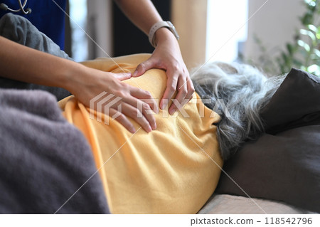 Physiotherapist massaging back muscles in area of shoulder blade of mature female patient Physiotherapist massaging back muscles in area of shoulder blade of mature female patient 118542796