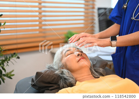 Female practitioner giving Reiki healing treatment to senior patient. Alternative medicine concept Female practitioner giving Reiki healing treatment to senior patient. Alternative medicine concept 118542800