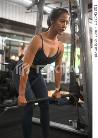 Focused sporty Asian woman doing deadlift exercise at the gym Focused sporty Asian woman doing deadlift exercise at the gym 118542801
