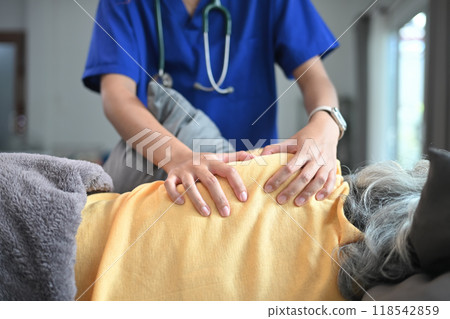Physiotherapist massaging back muscles in area of shoulder blade of mature female patient 118542859