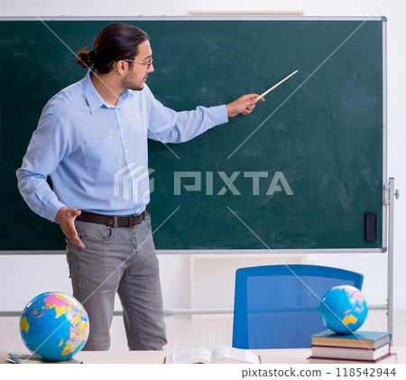Young male geography teacher in front of blackboard Young male geography teacher in front of blackboard 118542944