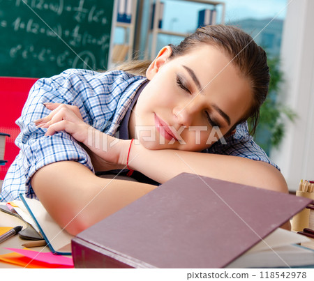 Female student with many books sitting in the classroom 118542978