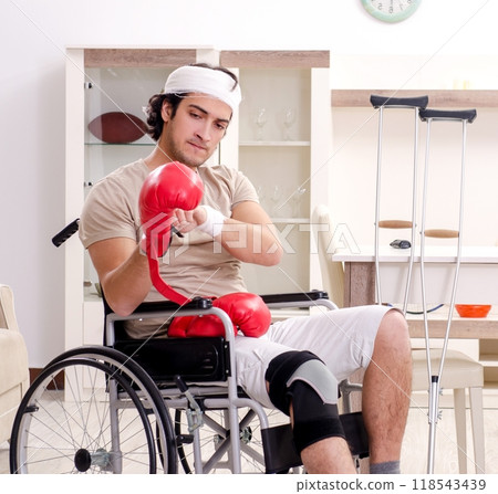 Injured young man doing exercises at home 118543439