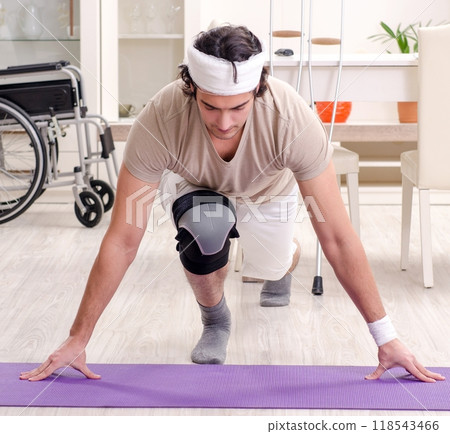 Injured young man doing exercises at home Injured young man doing exercises at home 118543466