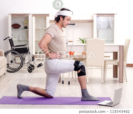 Injured young man doing exercises at home 118543482
